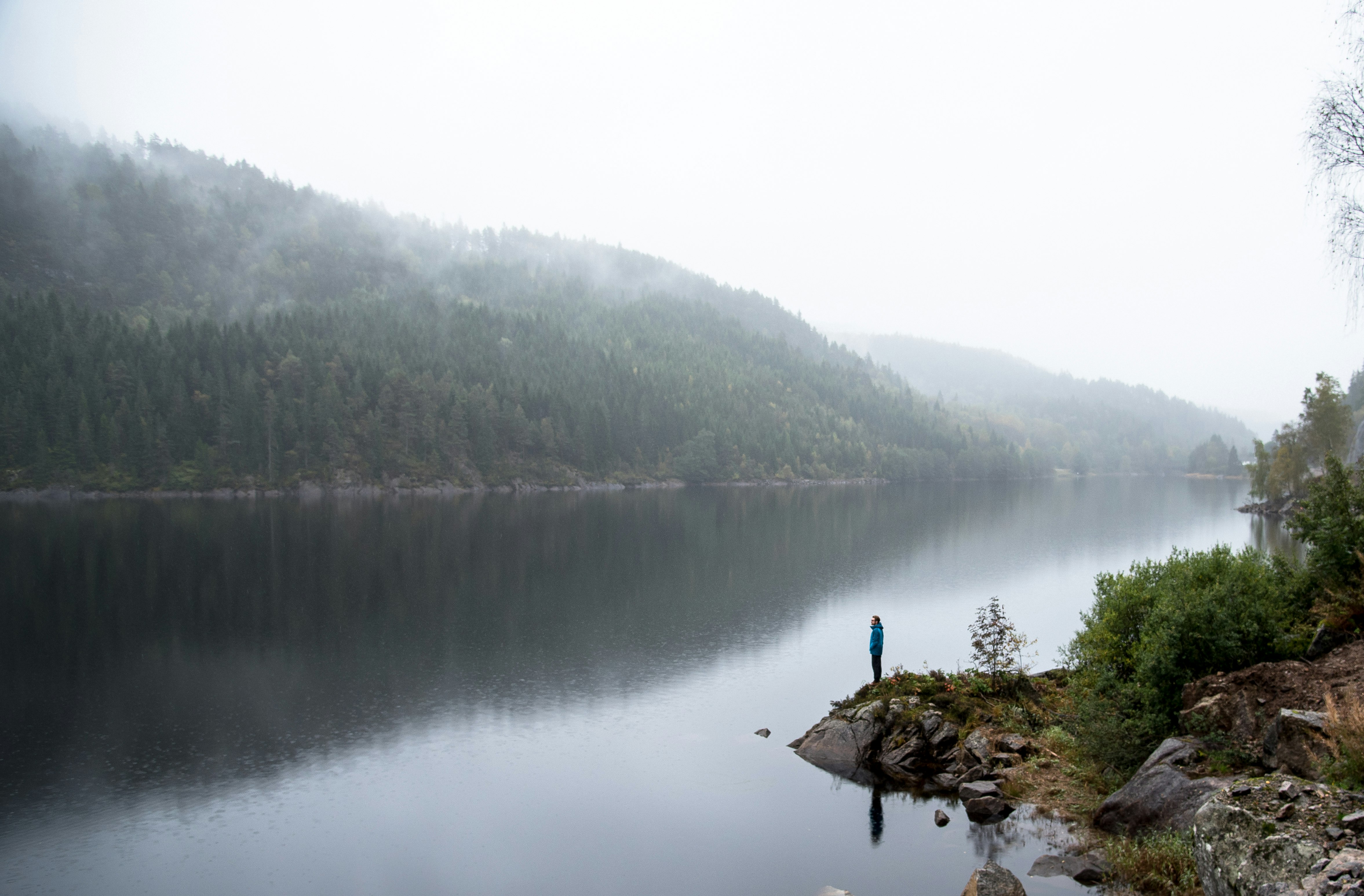 man standing on edge of land beside body of water